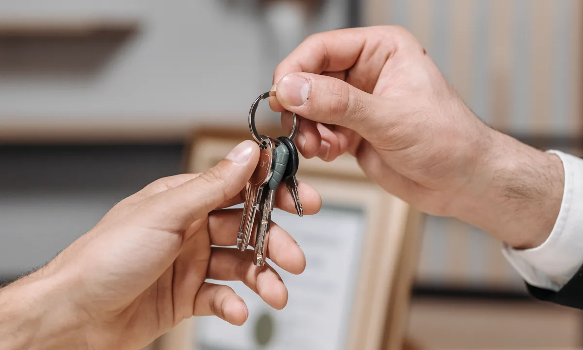 One person handing a set of house keys to another during an ownership transfer