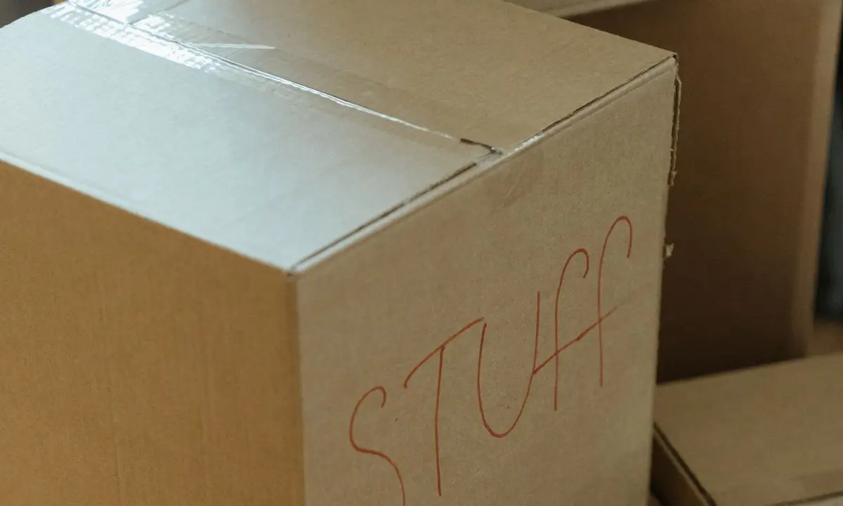 Stacked cardboard moving boxes, one labeled by hand