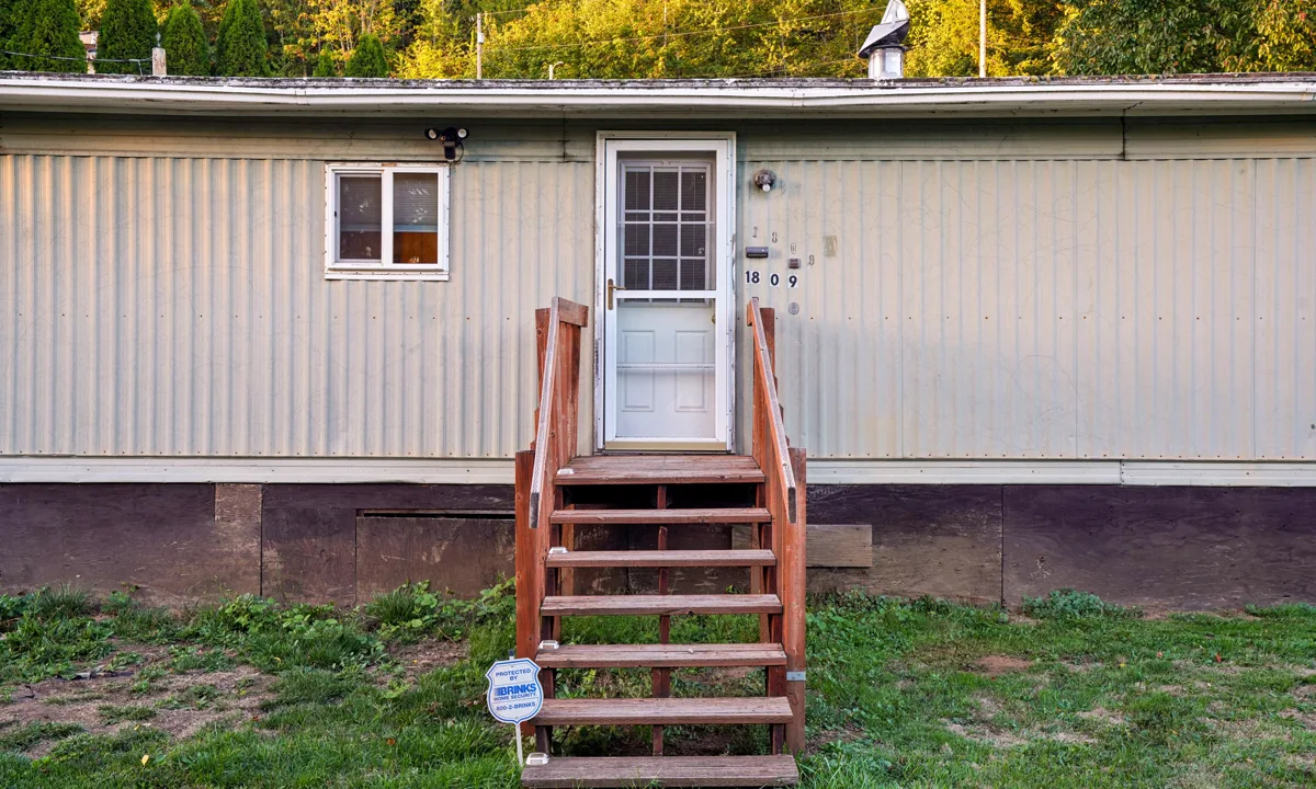 Exterior of a manufactured home with wooden entry steps and a grassy yard