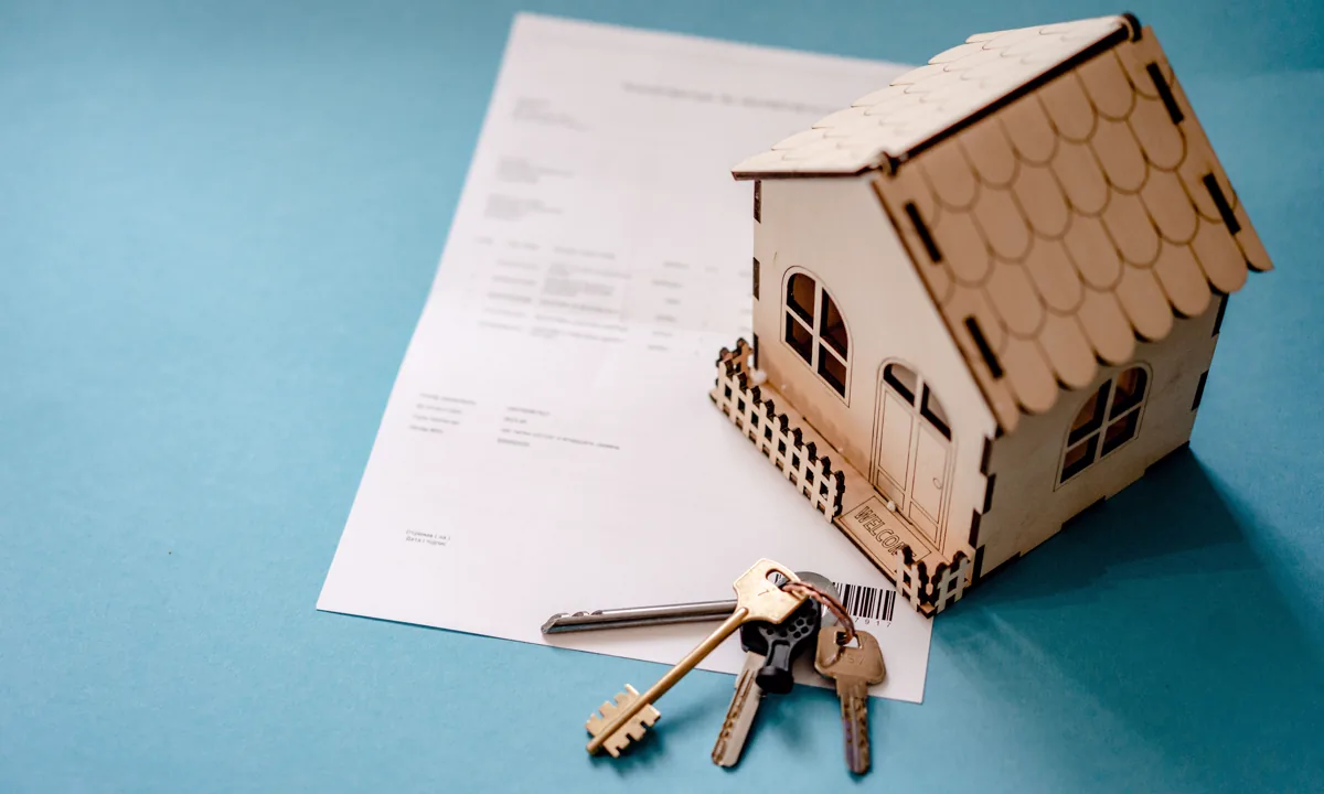 House model, keys, and purchase contract on a table