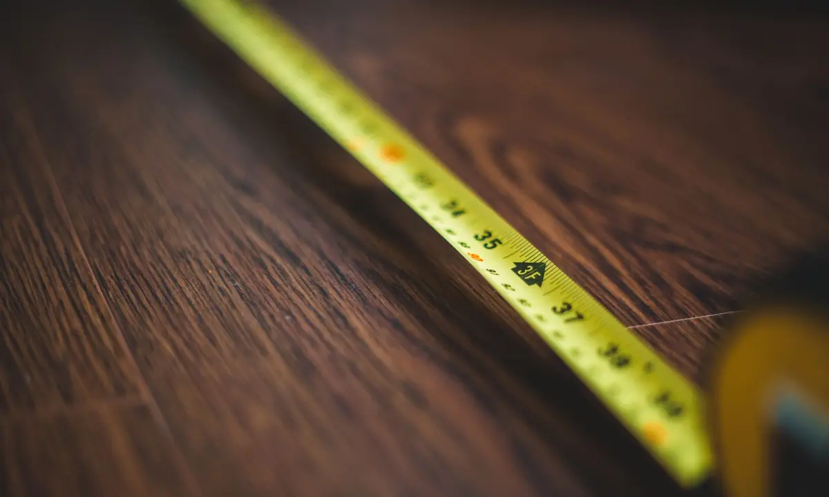 Yellow tape measure extended across a wooden floor