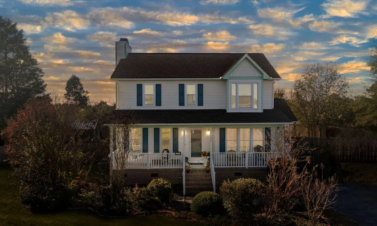 Two-story house with a white front porch and blue shutters at dusk